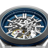 Brushed silver-toned skeleton watch, blue bezel, blue dial ring. Silver-toned hands, hour markers, visible automatic movement