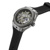 Gunmetal-toned watch with angular case, skeletonized dial showing silver-toned gears and gold-toned markers, and a black ribb