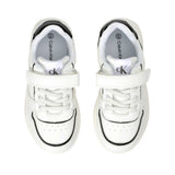 White low-cut sneakers with white laces, a single velcro strap, black collar trim, and black outlines on the toe and sides. '