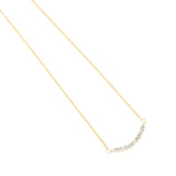 Gold-toned fine link chain necklace with a curved bar pendant set with a row of clear, round, faceted stones.