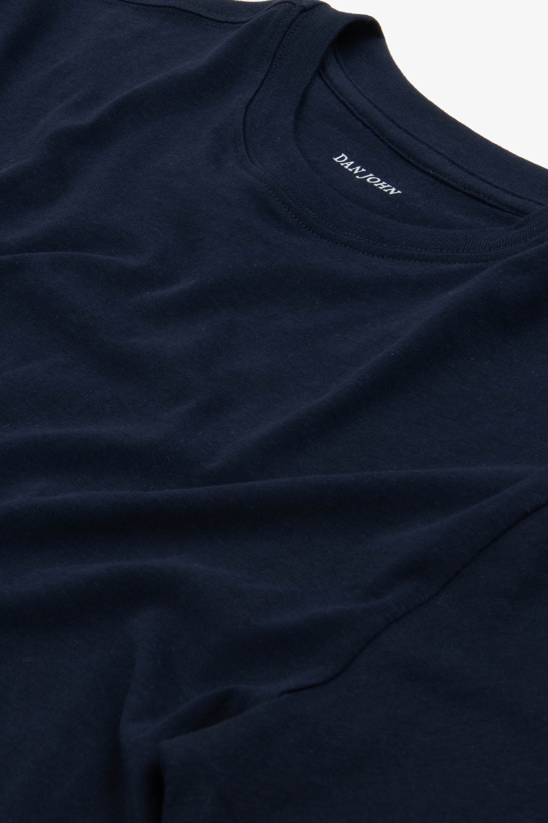 Dark navy blue short-sleeve t-shirt with a ribbed crew neck. 'DAN JOHN' is printed in white on the inside back collar.