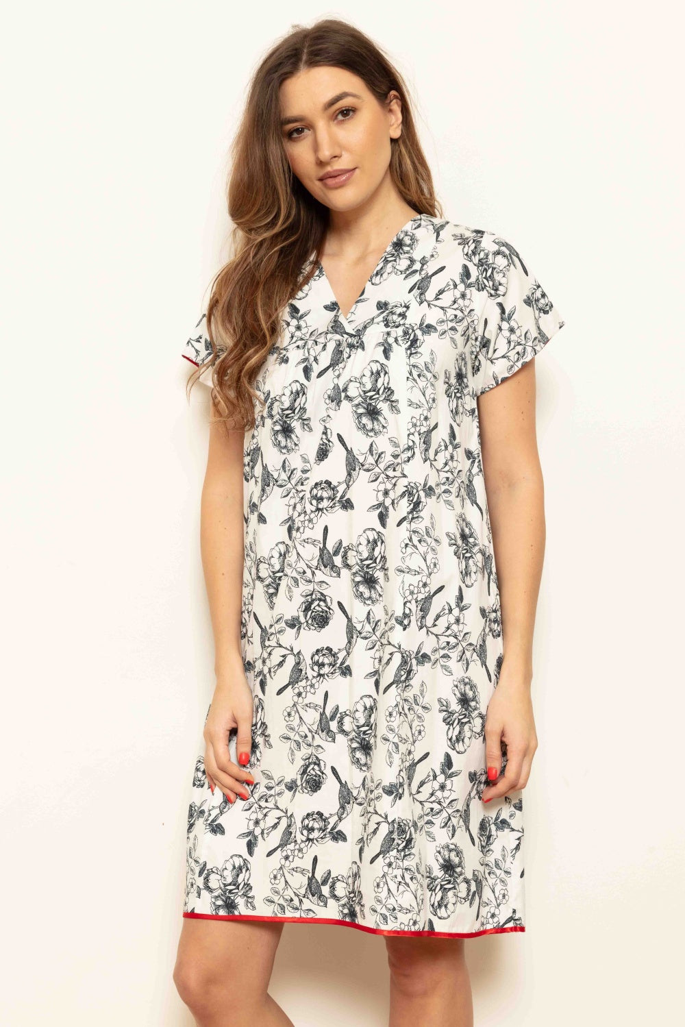 White V-neck dress with navy floral and bird print, short cap sleeves, gathered bodice, and red trim on sleeves and hem.