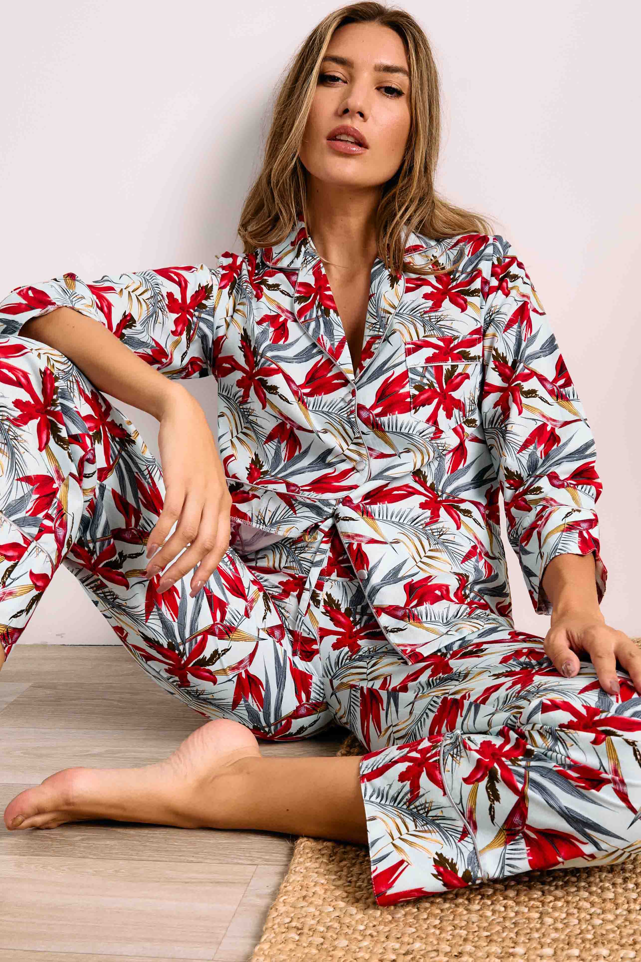 Crimson red, grey, and gold-toned tropical print PJ set on light blue. Button-up top with white piping and matching pants.