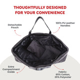 Black quilted changing bag with PU leather handles. Open main compartment contains a detachable pouch and an internal zippere