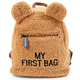 Beige curly faux fur children's backpack with teddy bear ears, a front zip pocket, and 'MY FIRST BAG' embroidered in black.
