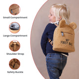 Teddy beige backpack with bear ears, front zipper pocket, and 'MY FIRST BAG' embroidery. Adjustable shoulder straps with a sa