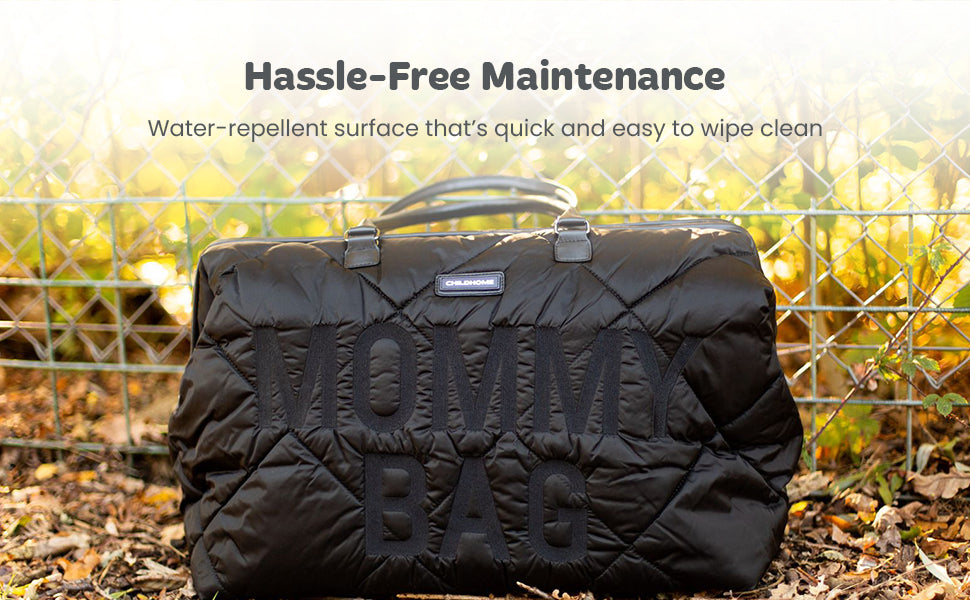 Black quilted 'Mommy Bag' with diamond stitching, two black top handles, and silver-toned hardware. Raised 'MOMMY BAG' text o