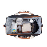 Black canvas mommy bag with light brown faux leather trim, white canvas handles with black text, and a light grey interior.