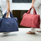 Dark blue crinkled fabric duffel bag with two top handles. 'MOMMY BAG' is embossed on the handles and vertically on the front