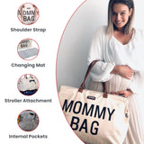 Off-white tote bag with 'MOMMY BAG' in black text, brown top handles, a shoulder strap, changing mat, and internal pockets.