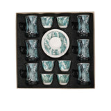 Top-down view of an 18-piece Casa Blu luxury drinkware set in a presentation box, featuring 6 tea glasses, 6 Cawa cups, and 6 saucers with a teal Lily of the Valley floral pattern.