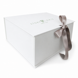 White rectangular gift box with a light green 'STORY LORIS SINCE 1949' logo on the lid, tied with a light brown satin ribbon.