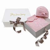 Pink sleepsuit with rounded collar and ballet shoe appliqué, paired with a matching pink beanie hat featuring a small satin b