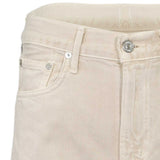 Close-up structural detail of the front waistband on the Citizens of Humanity ecru jeans, highlighting the branded metal button, fly stitching, and coin pocket.