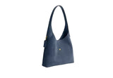 Three-quarter side view of the blue Coach Brooklyn hobo bag showing the wide shoulder strap and leather hangtag.