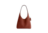 Front view of the Coach Brooklyn Shoulder Bag brown leather featuring a slouchy silhouette and gold-tone magnetic snap detail on the front pocket.