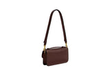 Side-profile view of the Coach Hamptons bag in dark maple leather, showcasing its slim depth and adjustable shoulder strap.