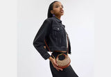 Woman holding a handbag against a white background.