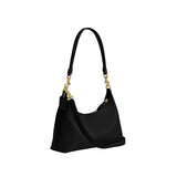 A three-quarter view of the Juliet bag in black leather, displaying the slim profile, detachable crossbody strap, and the iconic leather hangtag.