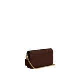 Side-angle view of a Coach Hayden crossbody bag in tan signature canvas featuring a gold-tone chain strap and a rust-colored leather hangtag.