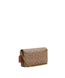 Side-angle view of a Coach Hayden crossbody bag in tan signature canvas featuring a gold-tone chain strap and a rust-colored leather hangtag.
