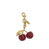 A gold-tone curb chain bag strap from Coach featuring various colorful charms, including a green dinosaur, red cherries, a black spider, and a signature 'C' logo, shown against a plain white background.