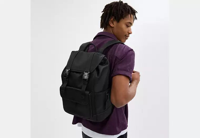 Person wearing a black backpack on a white background.
