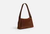 Side-angle view of the Coach Juliet bag highlighting the soft suede texture and the integrated leather shoulder strap.