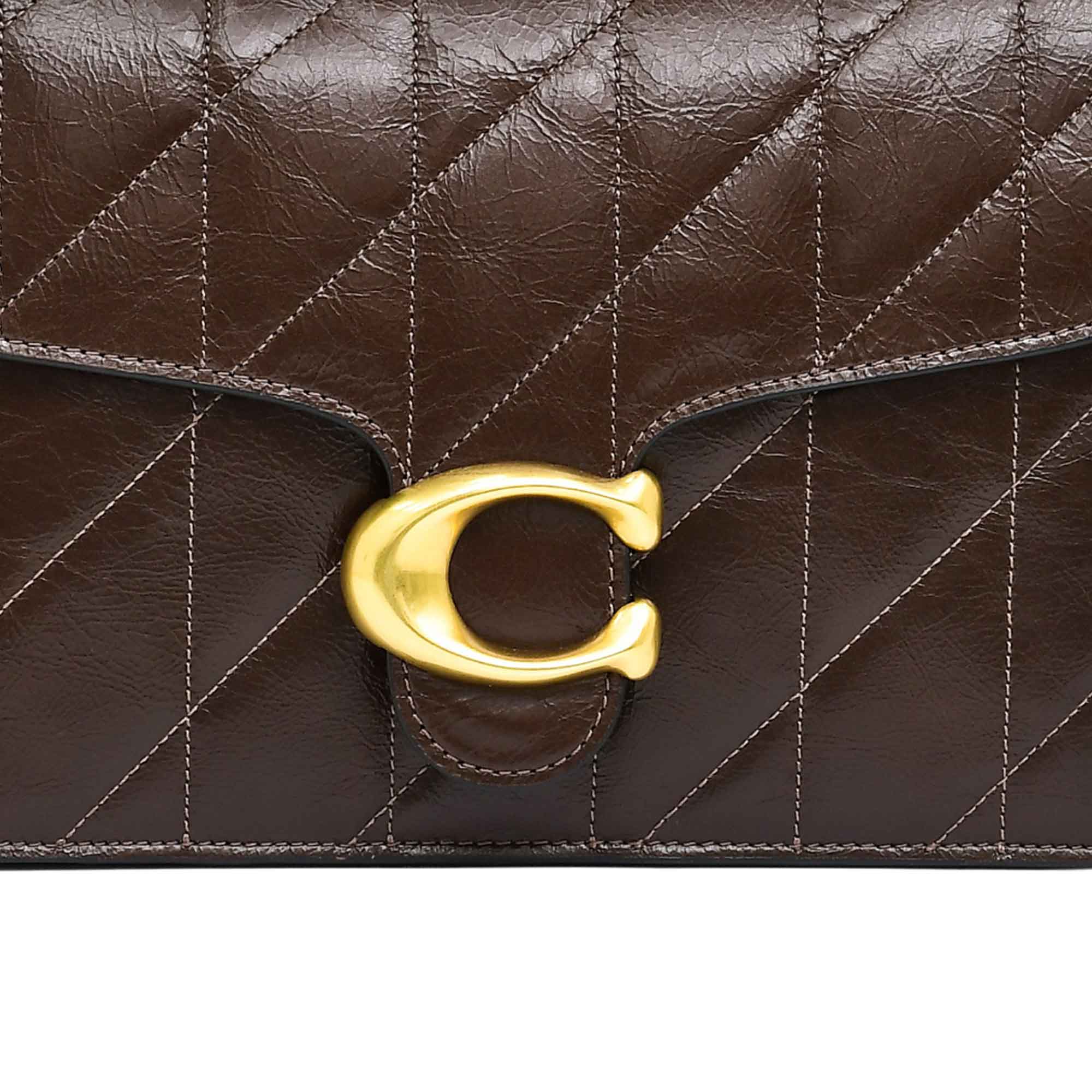 Detailed view of the wide maple brown leather crossbody strap for the Coach bag, showcasing the matching brown prong buckle, adjustment holes, and heavy-duty dogleash swivel hook.