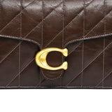 Detailed view of the wide maple brown leather crossbody strap for the Coach bag, showcasing the matching brown prong buckle, adjustment holes, and heavy-duty dogleash swivel hook.