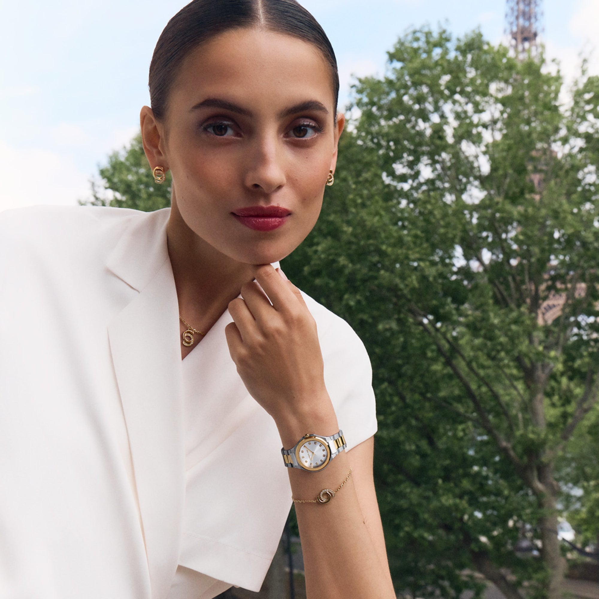 Still life collection layout showcasing the Marina gold bracelet next to its matching monogram necklace, earrings, and a luxury watch.
