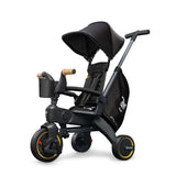 Black Doona Liki Trike S5 with yellow wheel accents, a canopy, safety harness, push handle, and storage bag.