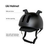 Black Liki helmet with two silicone horns, two vertical air flow openings, a fabric visor, and black adjustable straps.