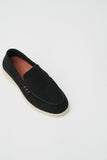 Black suede loafer with light beige sole, reddish-brown insole, and two small tan decorative elements on the side.