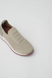 Single beige knitted slip-on runner shoe with a textured mesh upper, ribbed collar, grey heel patch, white midsole, and maroo
