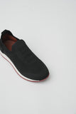 Black knitted slip-on runner with a white midsole, dark red outsole, and brown interior lining. Features ribbed collar and te