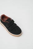 Black suede low-top sneaker with three hook-and-loop straps, a brown leather lining, and a light brown sole with a white stri