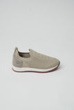 Light tan knit slip-on sneaker with textured toe, suede-like heel with embossed logo, white midsole, and maroon outsole.