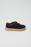 Black suede-like sneaker with two hook-and-loop straps, a brown collar lining, a white midsole stripe, and a thick tan rubber