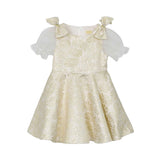 Front view of a David Charles girls' ivory dress with gold metallic starburst patterns, sheer glitter puff sleeves, and jeweled shoulder bows.