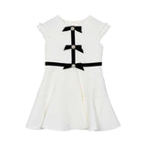 Front view of a David Charles ivory tweed girls' dress featuring black velvet bows with crystal centers and ruffled cap sleeves.