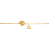 A flat close-up shot focusing on the center of the Escada Margarete bracelet, highlighting the textured ridges of the golden scallop shell and the adjacent dangling cutout back-to-back EE logo.