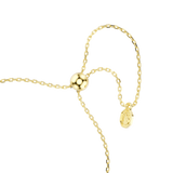 A macro close-up view of the Swarovski Magic bracelet's adjustable sliding bead fastener, showing the highly polished 18K gold finish and the dangling chain ends tipped with a branded octagonal swan tag.