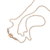 A close-up studio overview of the Aigner Iva rose gold necklace beautifully coiled on a white surface, highlighting the polished 'A' logo emblem flanked by graduated bezel-set clear crystals and the fluid construction of the chain links.