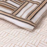Duvet cover set with two patterns: one with thick white, tan, and navy brushstroke blocks; another with thin tan herringbone