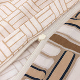 Cream duvet cover with a light cream zipper. One side has a tan brick pattern, the other features abstract brown, cream, and