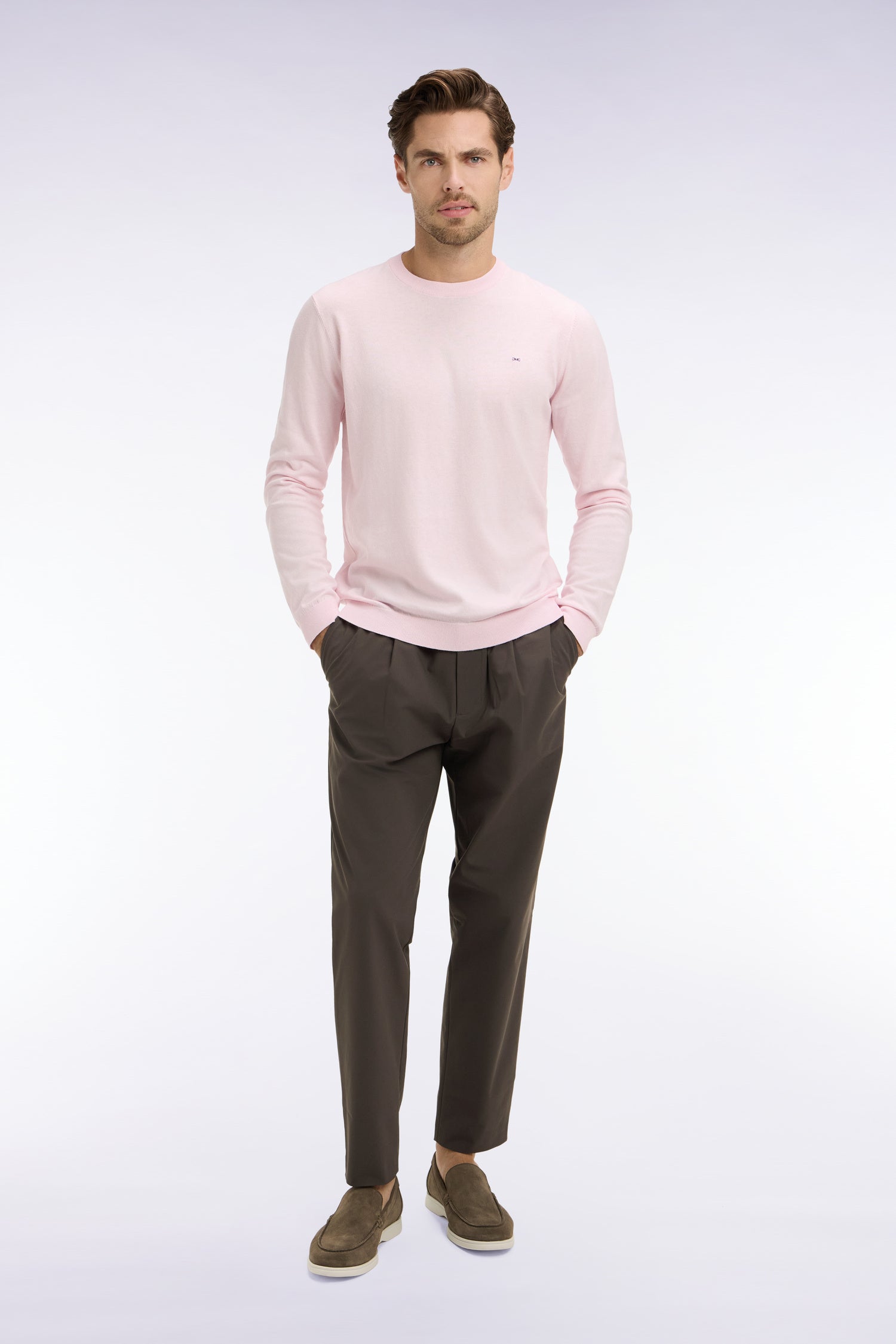 Dark olive-brown pleated trousers with a relaxed fit and tapered, ankle-length legs. Features a single pleat on each front le