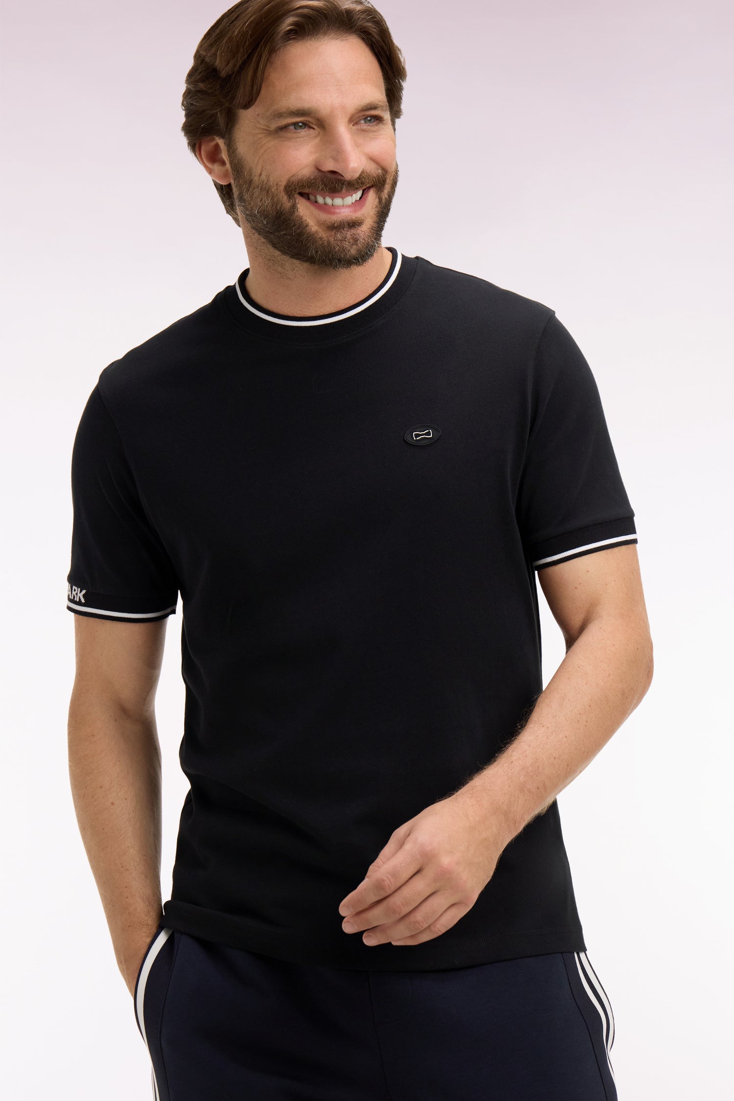 Black short-sleeve t-shirt with a ribbed crew neck and cuffs, both featuring two white stripes. Small black rectangular chest