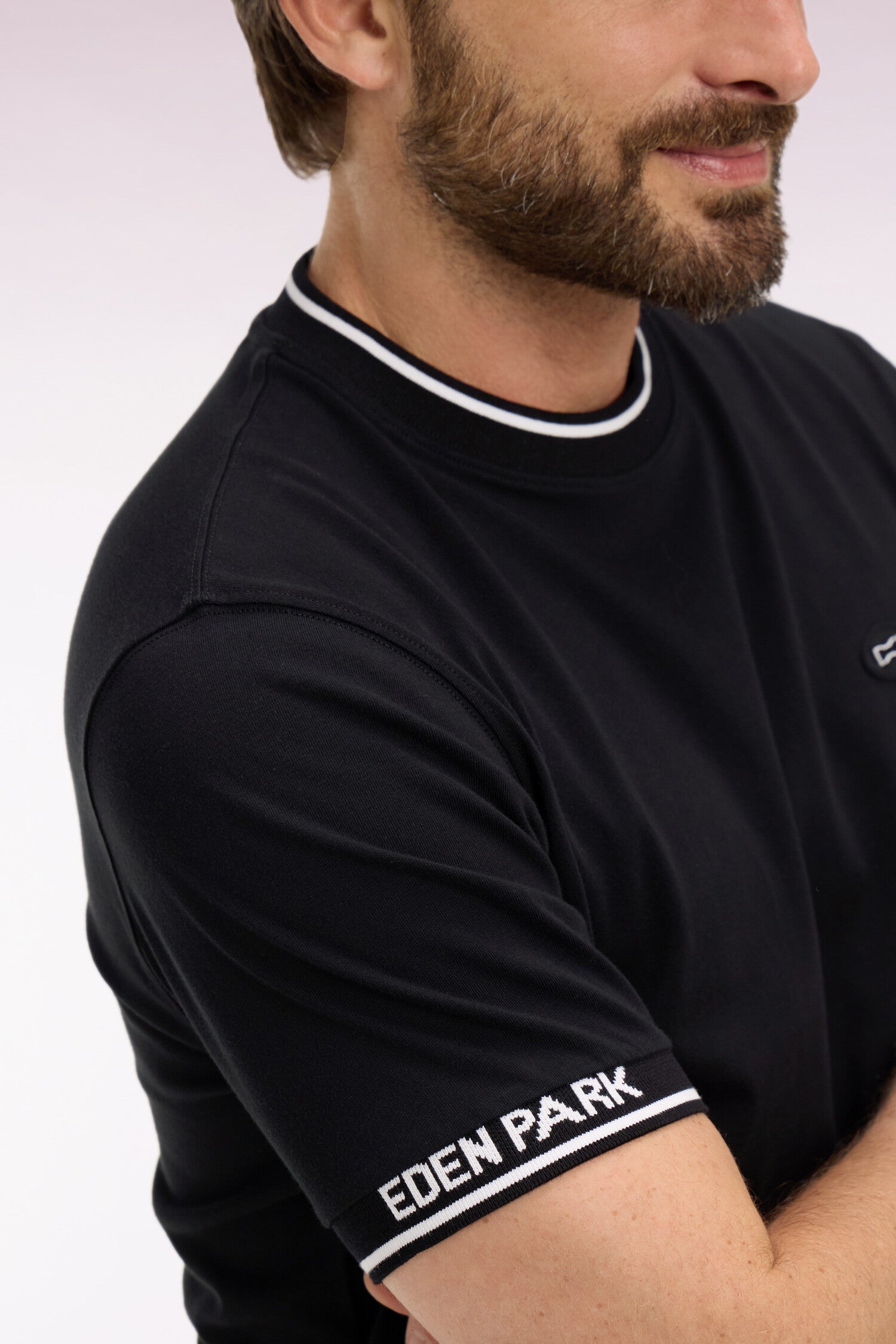 Black short-sleeve t-shirt with a crew neck featuring two white stripes. Ribbed cuffs have "EDEN PARK" text and two white str