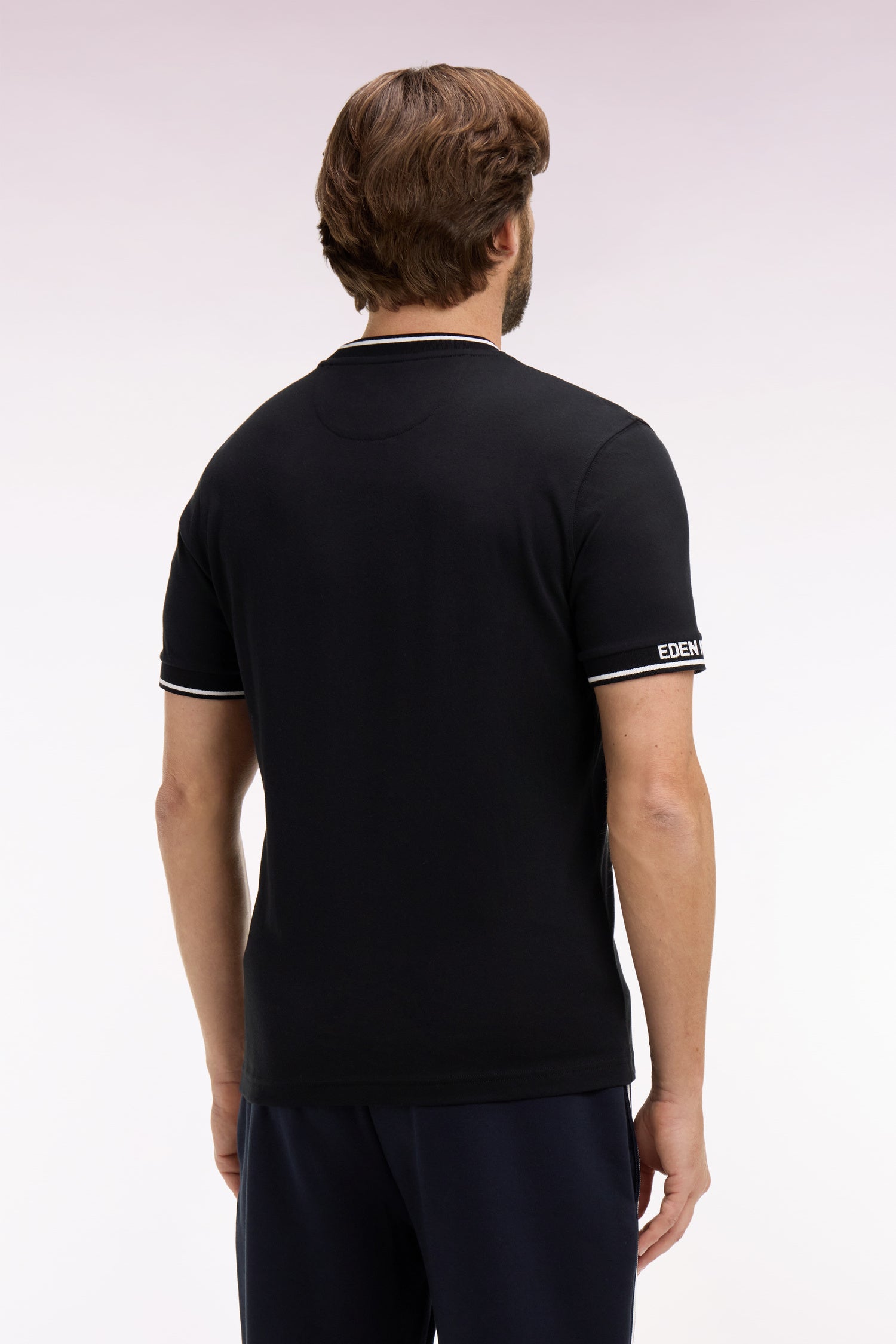Black short-sleeve t-shirt with white striped crew neck and ribbed cuffs. 'EDEN' text on the right cuff.